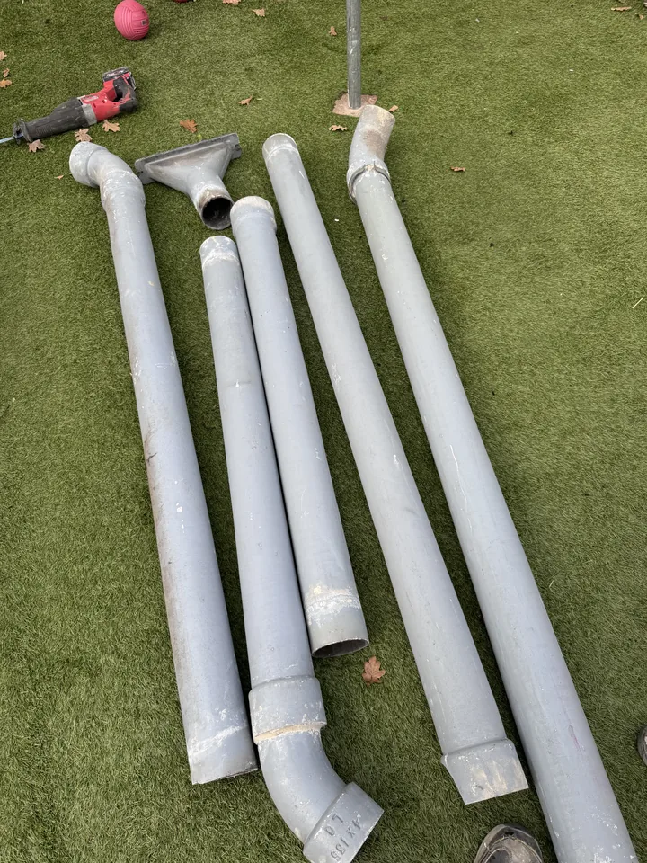 Removed downpipe sections and fittings laid out on grass