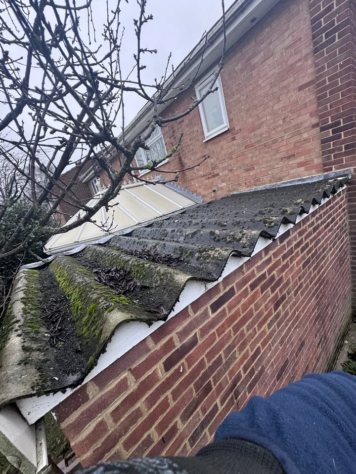 Old corrugated lean-to roof beside a brick wall